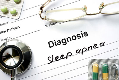 This is a picture of a paper saying Diagnosis Sleep apnea it has some green pills on the left top corner and a pair of reading glasses on the top right corner and it has green and yellow capsules with the end of a stethoscope on the bottom left corner