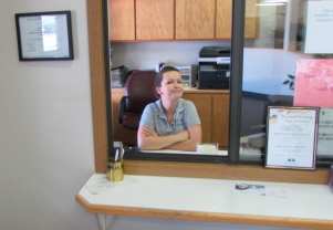 A receptionist behind a desk is welcoming with a smile