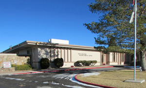 White Mountain Regional Medical Center building with a flag pole, trees and bushes in the front
