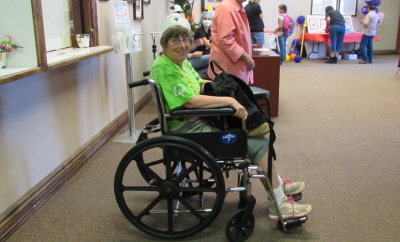 An elderly woman with a sweet smile is sitting in a wheel chair