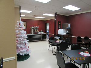 This is a lunchroom with red walls and a white Christmas tree on the left hand side of the picture